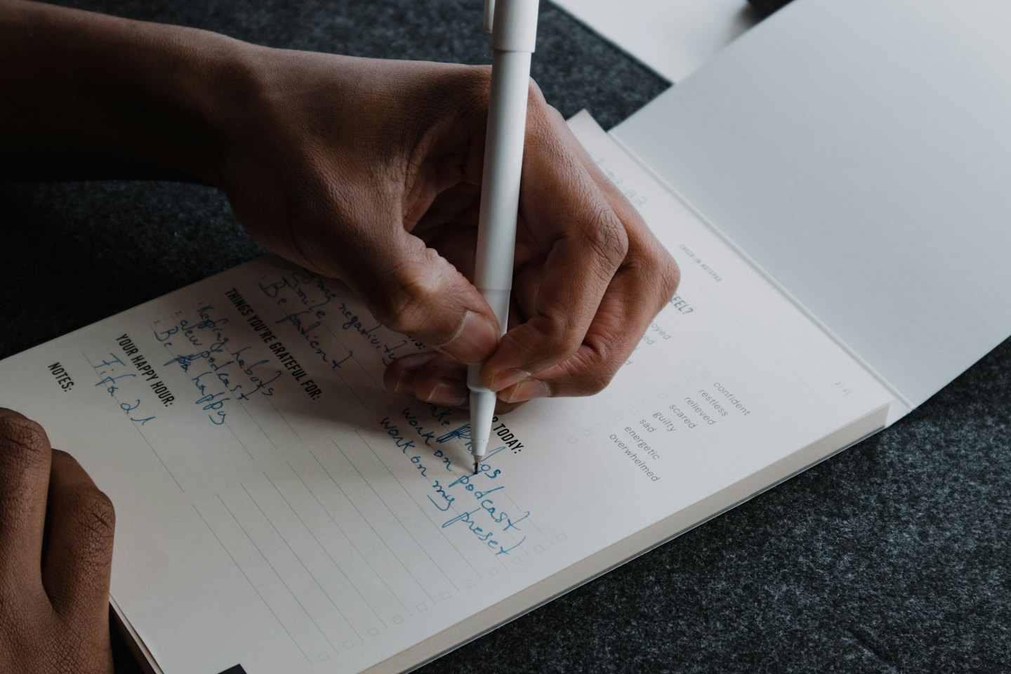 Persona che scrive su un'agenda con una penna blu.